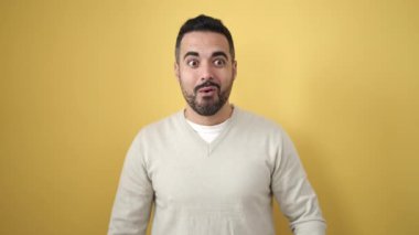 İzole edilmiş sarı arka planda sürpriz bir ifadeyle duran İspanyol genç adam.