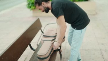 Young hispanic man musician playing classical guitar at park