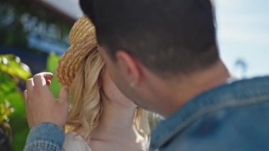 Sokakta öpüşen yaz şapkası takan erkek ve kadın.