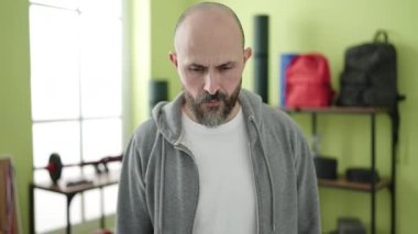 Spor merkezinde rahat bir ifadeyle duran genç kel adam.