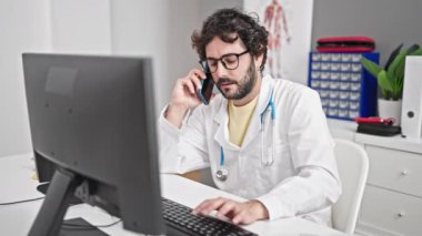 Genç İspanyol doktor, klinikte bilgisayarla konuşuyor.