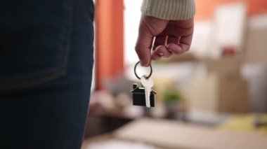 Young hispanic man holding key at new home