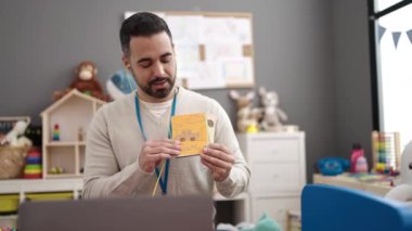 Young hispanic man working as teacher teaching online words lesson at kindergarten