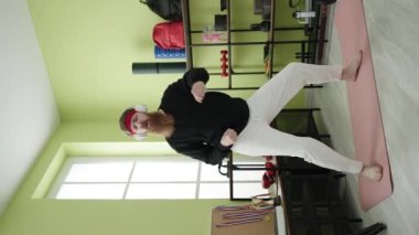 Genç kızıl saçlı adam spor merkezinde müzik dinliyor.