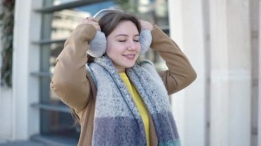 Sokakta kendine güvenen, kulaklık ve eşarp takan genç sarışın kadın.