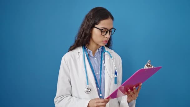 年轻美丽的惊慌失措的女医生正在用剪贴板上的蓝色背景阅读文档 — 图库视频影像