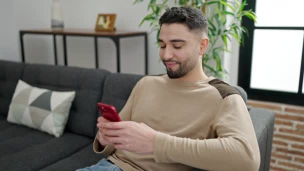 Νεαρός Άνδρας Arab Χρησιμοποιώντας Smartphone Κάθεται Στον Καναπέ Στο Σπίτι — Αρχείο Βίντεο