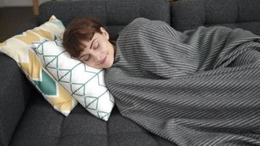 Young caucasian woman sleeping on the sofa covered with blanket at home