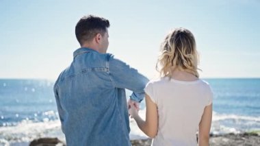 Kadın ve erkek deniz kenarında birbirlerine sarılıyorlar.