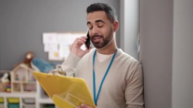 Genç İspanyol anaokulu öğretmeni anaokulunda akıllı telefondan doküman okuyor.