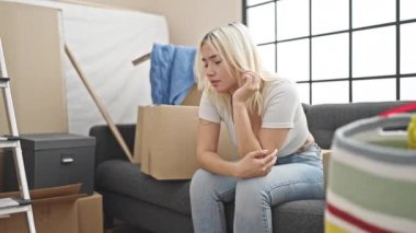 Genç, güzel, İspanyol bir kadın yeni evinde rahat bir ifadeyle koltukta oturuyor.