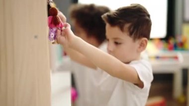 Sevimli çocuklar rahat bir ifadeyle anaokulunda oyuncak bebeklerle oynuyorlar.