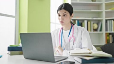 Genç, güzel İspanyol kadın doktor kütüphane üniversitesinde video görüşmesi yapıyor.
