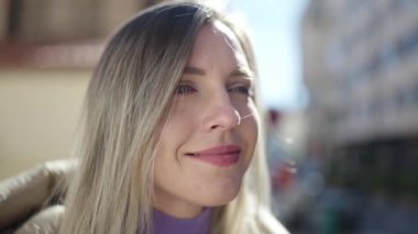 Young blonde woman smiling confident looking to the side at street