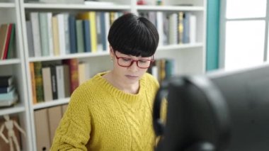 Young chinese woman student using computer stressed at library university