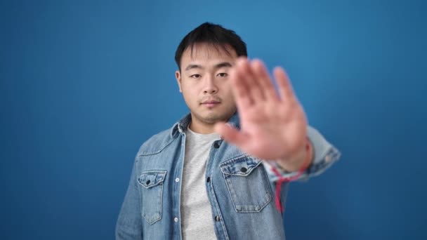 若いです中国人男ありますストップジェスチャーとともに手上の隔離された青の背景 — ストック動画