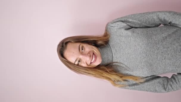 孤立したピンクの背景を指摘する自信を持って微笑む若い白人女性 — ストック動画