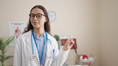 Klinikte gülümseyen genç, güzel İspanyol kadın doktor.