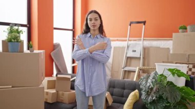 Yeni evdeki odada kollarını kavuşturup gülümseyen güzel İspanyol kadın.