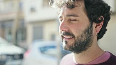 Young hispanic man looking to the sky with serious expression at street