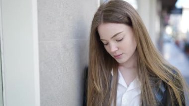 Sokakta ciddi bir ifadeyle duran genç sarışın kadın.