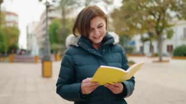 Middle age woman smiling confident reading book at park