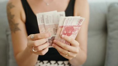 Genç bir kadın evde İzlanda Kronuru banknotlarını sayıyor.