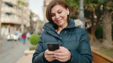 Sokak ortasında müzik dinleyen ve dans eden orta yaşlı bir kadın.