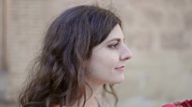 Genç ve güzel İspanyol kadın sokakta ciddi bir ifadeyle müzik dinliyor.