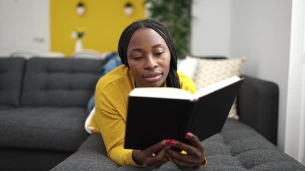 African Woman Reading Book Lying Sofa Home — Stockvideo