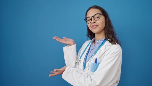 年轻美丽的惊慌失措的女医生带着自信的笑容 呈现在孤独的蓝色背景上 — 图库视频影像