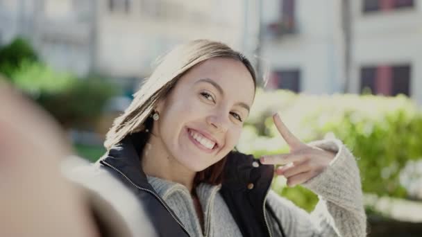 年轻美丽的惊慌失措的女人微笑着自信地在公园里用相机自拍 — 图库视频影像