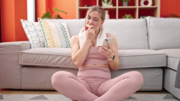 Genç Sarışın Kadın Evde Akıllı Telefon Kullanarak Elma Yiyor — Stok video