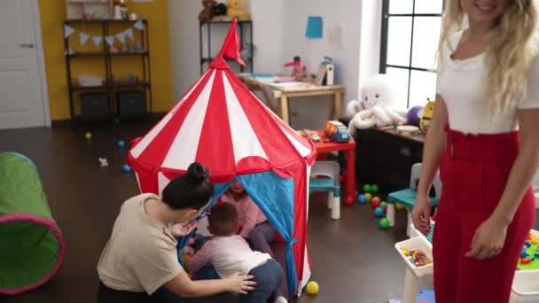 幼儿园地板上坐着男孩和女孩在马戏团帐篷上玩耍的教师 — 图库视频影像