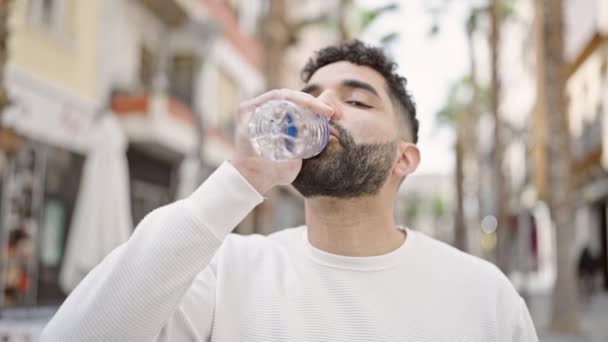 Jonge Spaanse Man Glimlacht Zelfverzekerd Drinken Fles Water Straat — Stockvideo