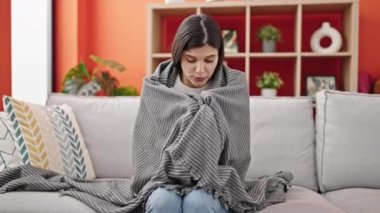 Kanepede oturan, battaniyeyle örtünen genç, güzel İspanyol kadın evde hasta.