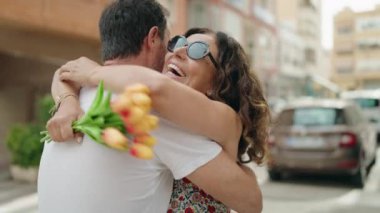 Kadın ve erkek sokakta çiçek buketiyle sürpriz yaparlar.