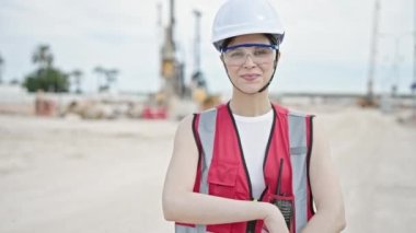 Güzel İspanyol kadın mimar gülümsüyor. Kollarını kavuşturup caddede duruyor.