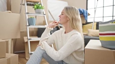 Genç sarışın kadın yeni evine şüpheli bir ifadeyle bakıyor.