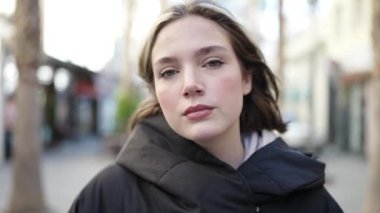 Sokakta yürürken yüzünde ciddi bir ifade olan genç sarışın kadın.