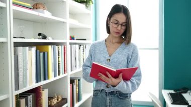 Kitap okuyan güzel İspanyol bir kadın kütüphanede sessizlik jesti yapıyor.