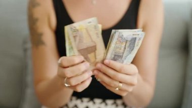 Evde peru sol banknotlarını sayan genç bir kadın.