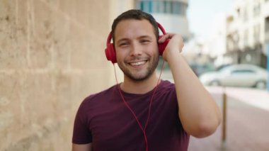 Sokakta müzik dinlerken kendinden emin gülümseyen genç adam.