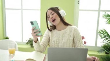 Young beautiful hispanic woman student smiling confident listening to music at home