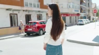 Sokakta kollarını kavuşturmuş genç Çinli bir kadın.