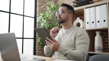 Young hispanic man business worker using touchpad working at office