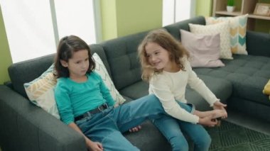 Sevimli kızlar kanepede oturup, ayaklarını gıdıklayarak gülüyorlar.