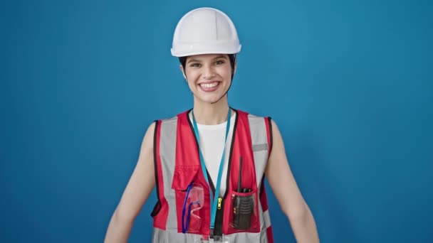 惊慌失措的女建筑工人微笑着 自信地在孤独的蓝色背景下做着强有力的手势 — 图库视频影像
