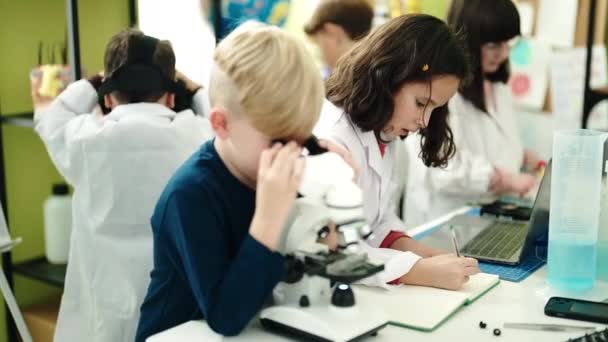 一组学生在实验室课堂上用显微镜在笔记本上写字 — 图库视频影像