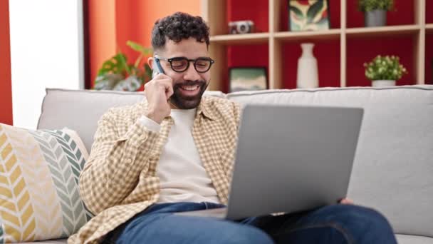 Hombre Hispano Joven Hablando Teléfono Inteligente Usando Ordenador Portátil — Vídeos de Stock